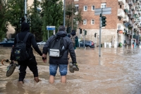 أشخاص يسيرون في شارع غمرته المياه في ميلانو- د ب أ