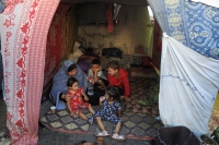امرأة فلسطينية نازحة فرت من منزلها بسبب غارات الاحتلال تجلس مع أحفادها في ملجأ مؤقت- رويترز