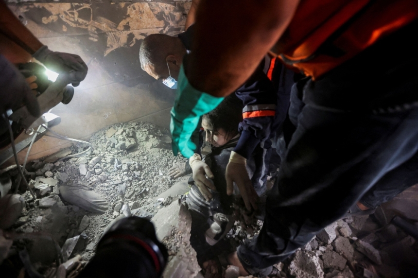 أفراد الطوارئ يعملون على إنقاذ فتاة فلسطينية في موقع غارات إسرائيلية على مبنى سكني - رويترز