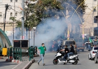 فلسطينيون يركضون للاحتماء من الغاز المسيل للدموع الذي أسقطته طائرة للاحتلال بالضفة- رويترز