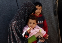 امرأة فلسطينية نازحة تجلس مع أطفالها- رويترز
