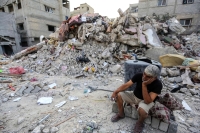 فلسطيني يجلس حزينًا على أطلال منزله في غزة
