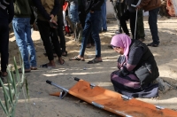 امرأة تبكي بينما يقوم الناس بدفن جثث الذين استشهدوا في غارة للاحتلال- رويترز