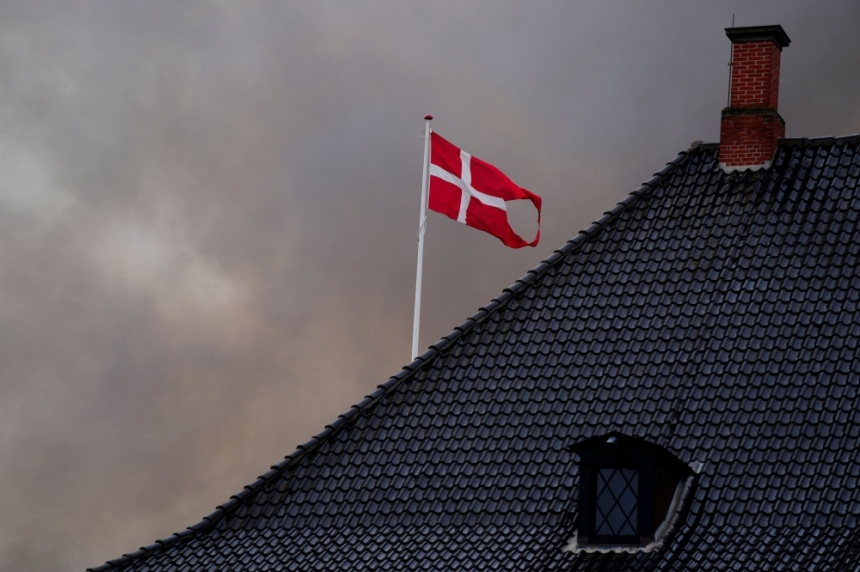 العلم الدنماركي يرفرف فوق وزارة المالية بينما يتصاعد الدخان أثناء حريق في البورصة القديمة - رويترز