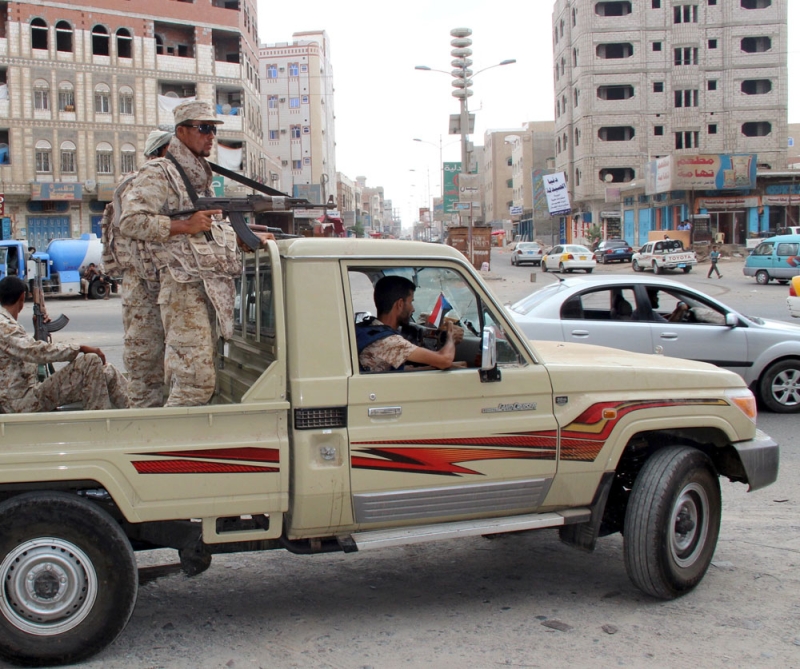 جنود يمنيون يقومون بدوريات في شارع بحي المنصورة في عدن (رويترز)