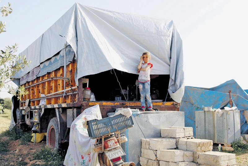 فتاة سورية تسكن وأسرتها في شاحنة بعد فرارهم من قصف الأسد لمدينة درعا (رويترز)