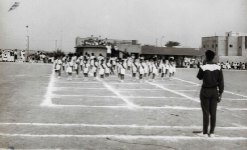 استعراض رياضي للمدرسة في سنة 1963.. وتبدو في وسط الصورة المباني الخشبية المهجورة المخيفة (أرشيف الكاتب)