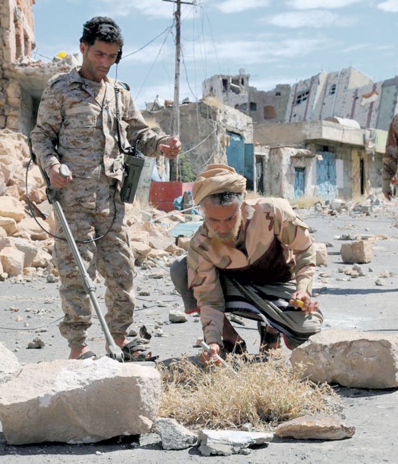 جنود من المقاومة الشعبية تطهر مواقع من الألغام بعد طرد الحوثيين منها (أ.ف.ب)