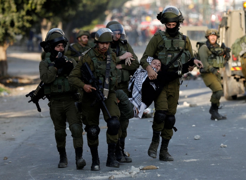  جنود إسرائيليون يعتقلون فتى فلسطينيا خلال احتجاجات بالقرب من مدينة نابلس (رويترز) 