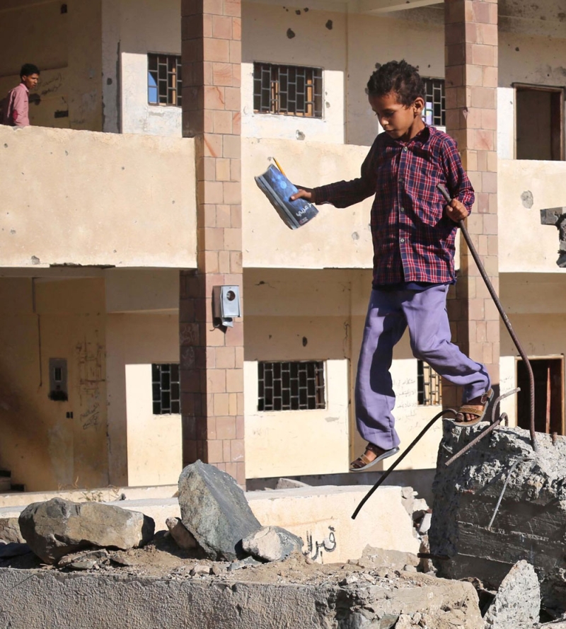 تلميذ يعتلي حطام جدران مدرسة في تعز (أ ف ب)
