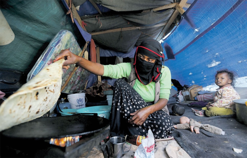 امرأة تصنع الخبز داخل خيمتها في مخيم للنازحين قرب صنعاء 