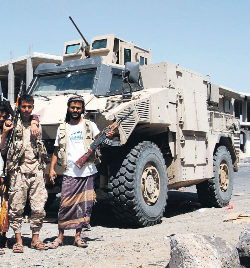 مقاتلون من الجيش والمقاومة الشعبية اليمنية يقفون أمام عربة مدرعة في المخا (أ.ف.ب) 