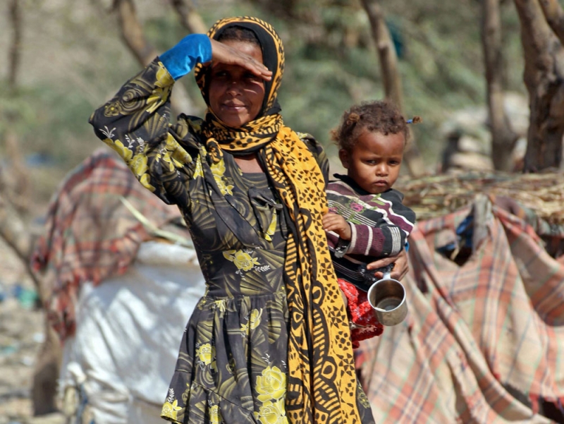 يمنية تحمل طفلها في مخيم للنازحين بضواحي جنوب تعز (أ ف ب)