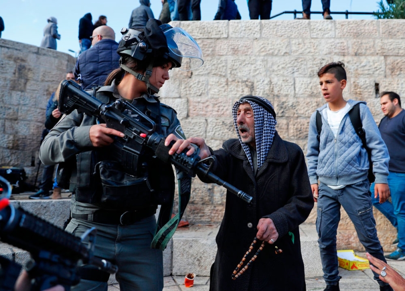 شيخ فلسطيني يجادل شرطية إسرائيلية خلال احتجاج على القرار (رويترز) 