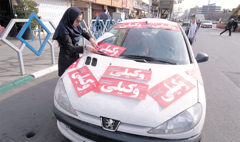 مؤيدة لمرشح برلماني تضع ملصقاته على سيارتها في طهران
