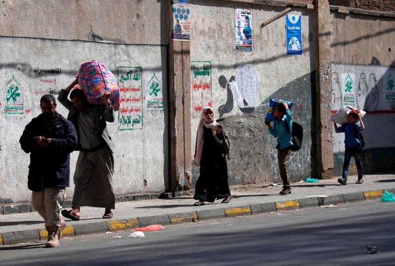 عائلة يمنية تحمل أمتعتها فرارا من اشتباكات الحوثيين وأنصار صالح (أ ف ب)