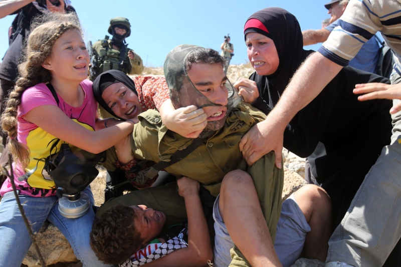 الصورة الأولى لـ «عهد» وهي تحاول تخليص شقيقها من قبضة جندي إسرائيلي (أ ف ب)