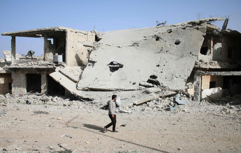سوري يمر بجوار مبنى دمرته طائرات الأسد في مدينة درعا الجنوبية (أ.ف.ب)