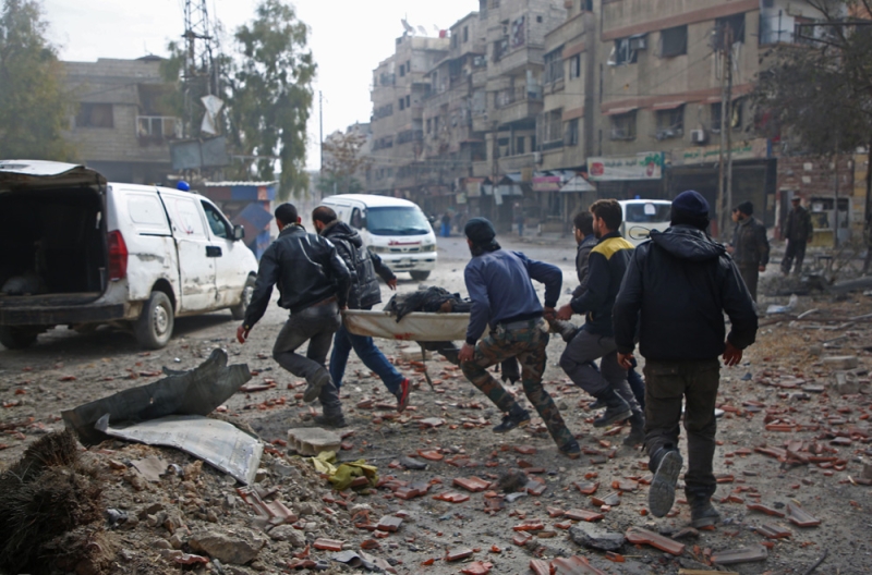 رجال الإنقاذ السوريون يجلون مصابا عقب غارة لنظام الأسد على كفر بطنا (أ.ف.ب)
