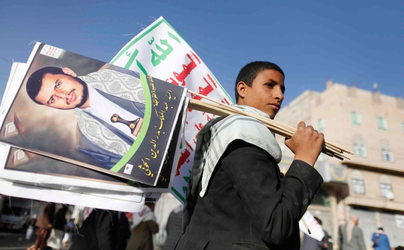شاب يمني يحمل اعلام بها صورة زعيم الحوثيين عبدالملك الحوثي