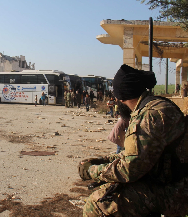 مقاتل من المعارضة السورية يراقب نقل مهجري الفوعة (أ ف ب)