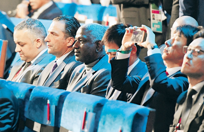 خوان انطونيو بيتزي يتوسط عادل عزت وماجد عبدالله أثناء مراسم قرعة كأس العالم (رويترز)