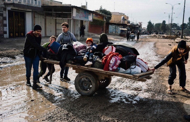 عائلة عراقية فارة من الموصل تعتلي عربة بأحد شوارع حي الزهراء