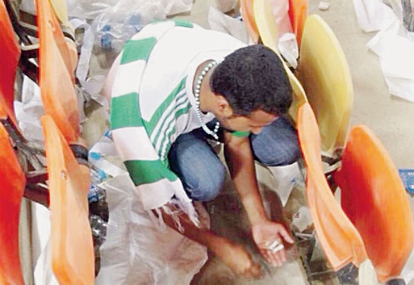 أحد جماهير الأهلي يقوم بتنظيف مقاعده عقب نهاية المباراة