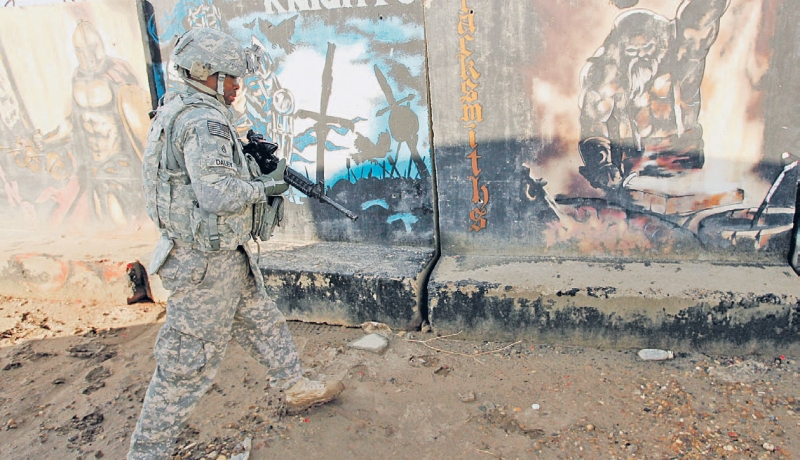 جندي أمريكي يقف أمام رسومات قديمة للجيش الأمريكي في قاعدة التاجي 
