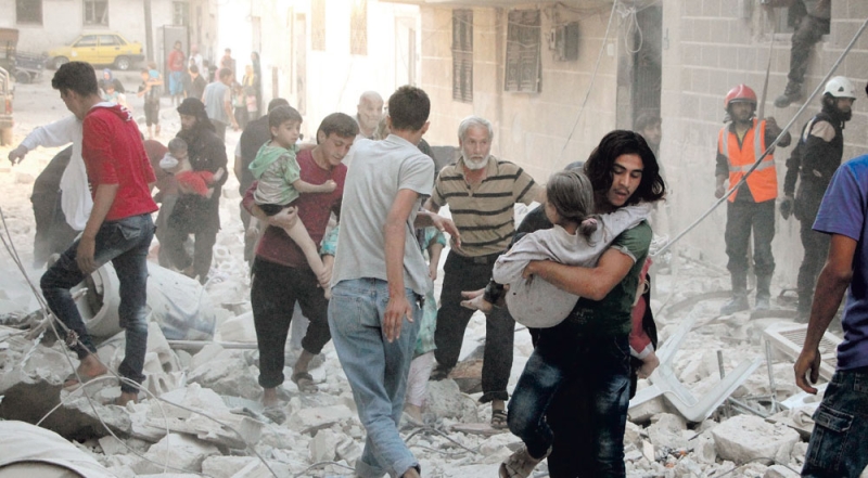 سوريون يحملون أطفالا جرحى وسط أنقاض مبان دمرتها غارة شمال غرب إدلب