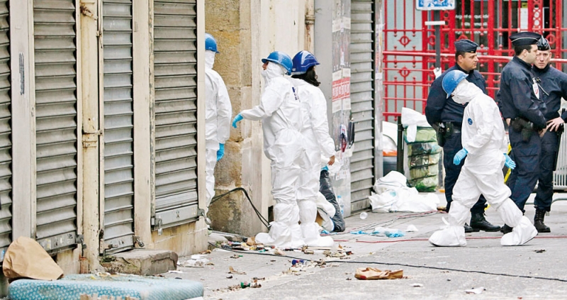 أفراد من الطب الشرعي خارج مبنى في سانت دينيس اقتحمه الأمن الفرنسي الأربعاء