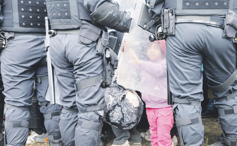طفلة تلمس درع أحد أفراد مكافحة الشغب السلوفينيين بعد عبور الحدود من كرواتيا