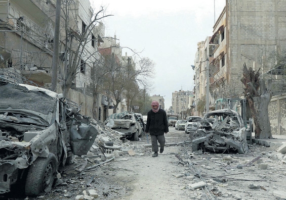 سوري بين مبان دمرتها غارات الأسد بالغوطة الشرقية (أ.ف.ب)
