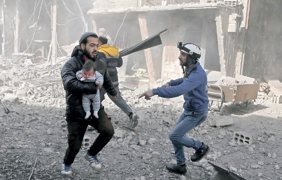 شاب يحمل رضيعا أصيب في القصف على الغوطة الشرقية (أ.ف.ب) 