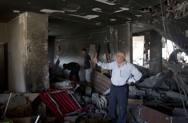 فلسطيني يعاين الأضرار التي لحقت بمنزله جراء العدوان الإسرائيلي (أ ف ب) 