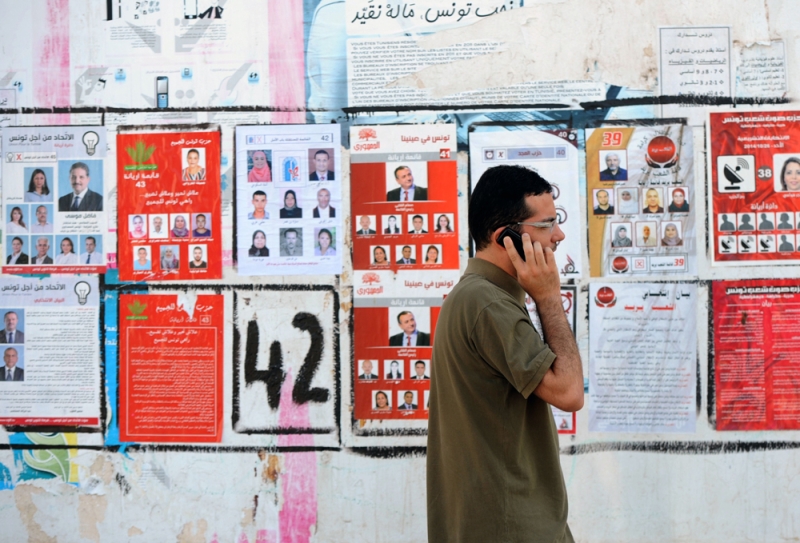 تونسي يمر أمام ملصقاتلمرشحي الانتخابية التشريعية (أ ف ب) 