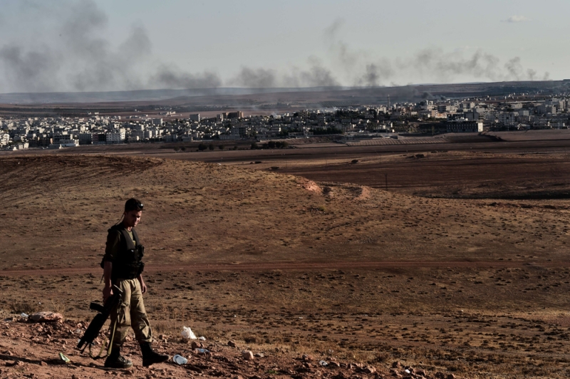 جندي تركي على الحدود التركية السورية وفي الخلف بلدة عين العرب (أ ف ب) 