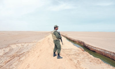  جندي تونسي يقف أمام خندق مائي يفصل البلاد عن ليبيا 
