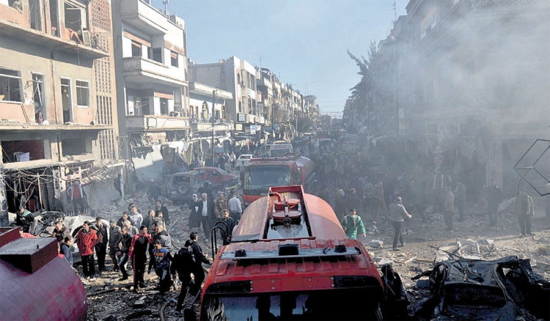 سوريون يتفقدون موقع التفجيرين في حي الزهراء بحمص