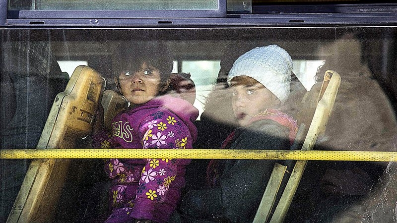 أطفال سورييون ينظرون من داخل حافلة نقل بحلب (الفرنسية)