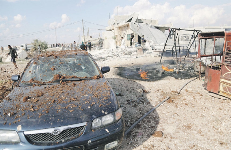 سوريون يتفقدون موقعاً في ريف إدلب قصفه الطيران الروسي بقنابل عنقودية