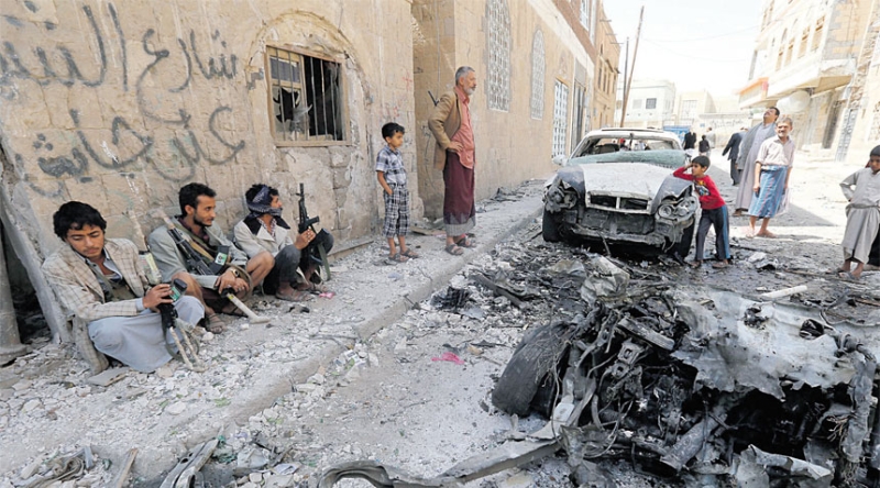 يمنيون يتفقدون مكان تفجير السيارة المفخخة في صنعاء
