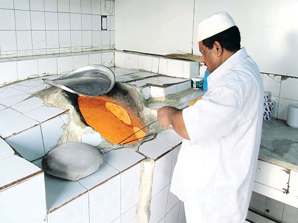 خباز يصنع الأرغفة بأحد المخابز الشعبية في الأحساء ( اليوم ) 