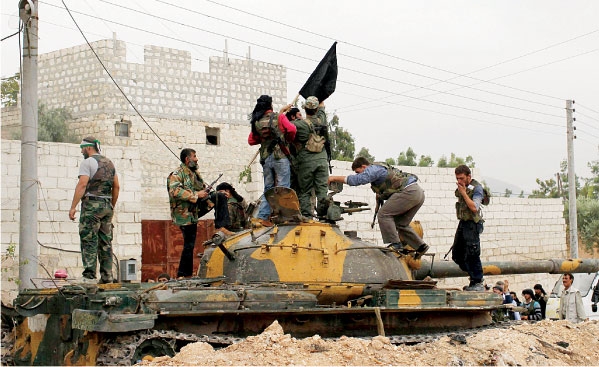 افراد من الجيش الحر يعتلون دبابة اسدية بعد الاستيلاء عليها .