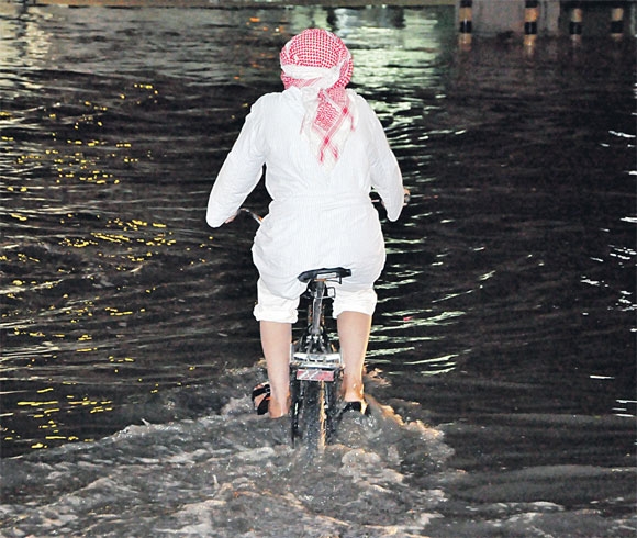 مواطن يعبر بحيرات المياه بدراجة هوائية (اليوم)