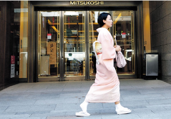 يابانية ترتدي الكيمونو الزي التقليدي للنساء تمر أمام أحد محلات بيع الملابس العصرية في العاصمة طوكيو. ( رويترز)