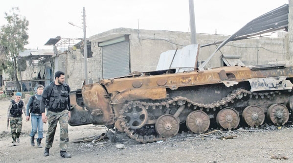 أفراد من الجيش الحر يمرون بمحاذاة دبابة اسدية عقب تدميرها