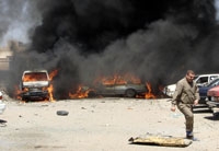سيارات تحترق وسحابة دخان فوق موقع تفجير في بغداد أمس	