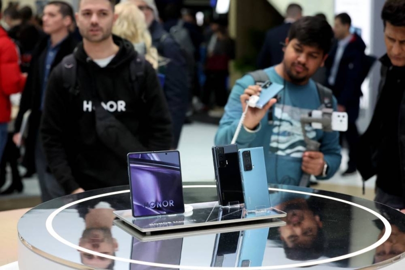 Visitors use their smartphones at the Mobile World Congress (MWC) honor stand.  MWC is the largest annual gathering of the telecommunications industry based in Barcelona this year. 