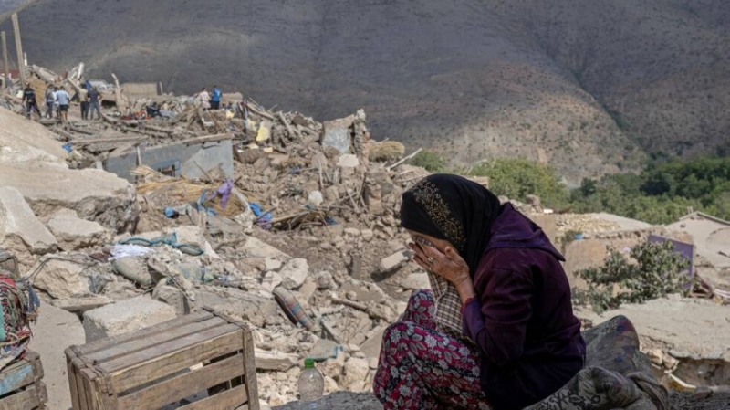 A devastated woman lies in front of rubble in central Morocco/AFP